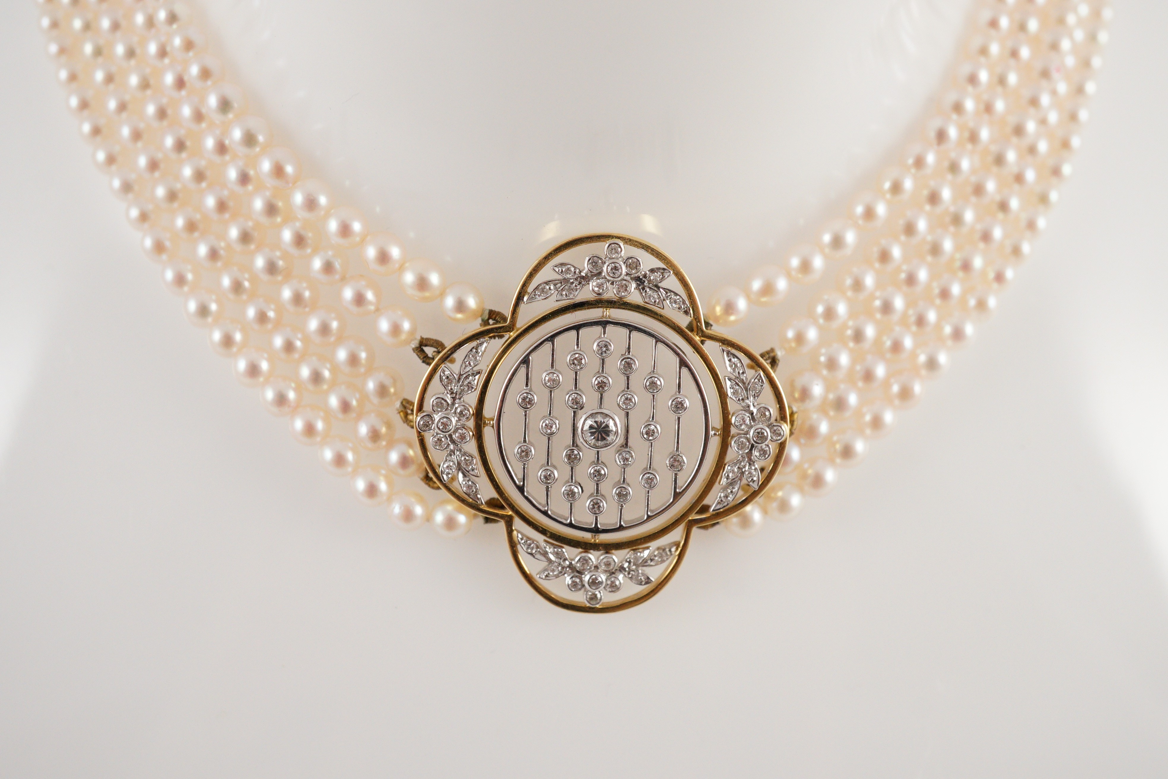 A quintuple strand seed pearl choker necklace, with pierced gold, platinum and diamond cluster set quatrefoil shaped clasp